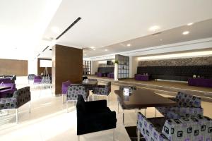 a restaurant with tables and chairs and purple chairs at Hotel Mediteran Plava Laguna in Poreč