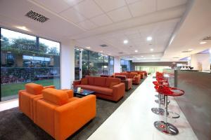 a waiting room with orange chairs and tables at Hotel Mediteran Plava Laguna in Poreč