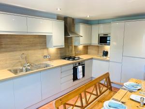 a kitchen with white cabinets and a wooden table at Spacious 2 Bed Apartment With Off Street Parking in Bath