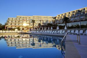 a hotel with chairs and a pool in front of a building at Hotel Mediteran Plava Laguna in Poreč