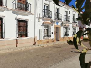 a row of white buildings with barred windows at Hostal Alcarayón Pilas in Pilas