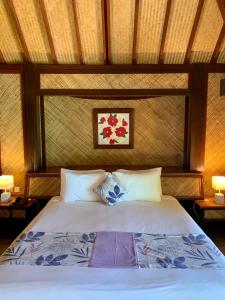 a bedroom with a bed with a white comforter and pillows at Maitai Bora Bora in Bora Bora