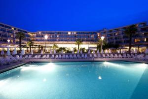 a large swimming pool in front of a hotel at night at Hotel Mediteran Plava Laguna in Poreč