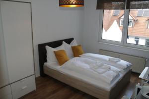 a bedroom with a bed with white sheets and orange pillows at Pension Michelangelo in Eisenach
