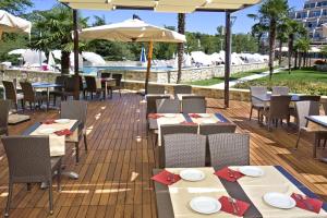 a restaurant with tables and chairs and a pool at Hotel Mediteran Plava Laguna in Poreč
