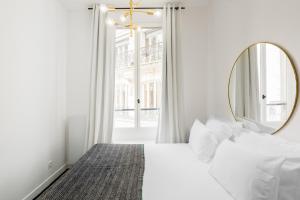 Dormitorio blanco con espejo y cama en Bourse Montorgueil, en París