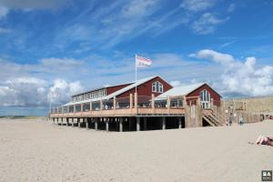 a building on the beach with a flag on it at Chalet Casa Quak in Petten