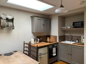 a kitchen with gray cabinets and a sink and a table at Little Doric in Shepton Mallet