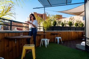 una mujer está de pie en un patio con una mesa y un taburete en Far Home Bernabeu, en Madrid