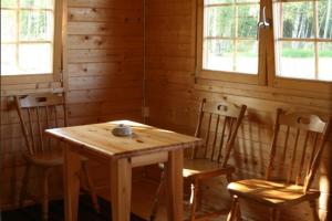 a wooden table and chairs in a room with windows at Uuskalda Sports and Holiday Village in Kärbla