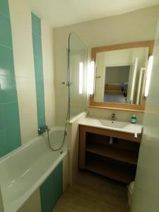 bagno con vasca, lavandino e specchio di RESIDENCE GOLFS DE VALESCURE 2 a Saint-Raphaël