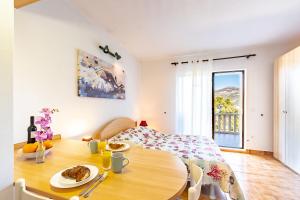 a room with a table and a bed and a room with a window at Apartments Tri Žala in Korčula