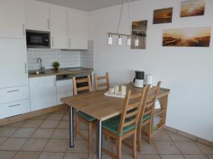 eine Küche mit einem Holztisch und Stühlen in der Unterkunft Wangeroogeweg 5a in Schillig