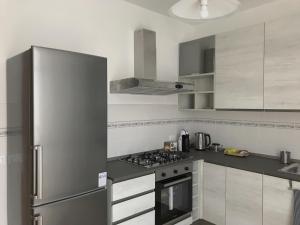 Il comprend une cuisine équipée d'un réfrigérateur en acier inoxydable et d'une cuisinière. dans l'établissement "Coccole nel borgo" 2min to outlet apartment with terrace, à Serravalle Scrivia