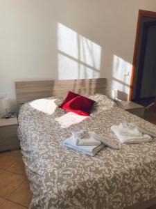 Una cama con toallas y una almohada roja. en "Coccole nel borgo" 2min to outlet apartment with terrace, en Serravalle Scrivia