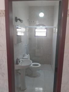 a white bathroom with a toilet and a sink at Casa do Paulo da Santissima in Tiradentes