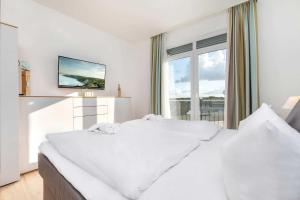 a white bedroom with a large bed and a window at Villa Wiederkehr Sonnendeck in Ostseebad Sellin