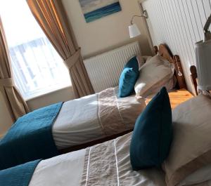 two beds in a bedroom with blue pillows at Bacchus Hotel in Sutton on Sea