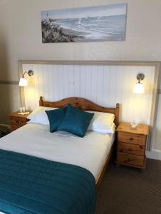 a bedroom with a bed with two night stands and two lamps at Bacchus Hotel in Sutton on Sea