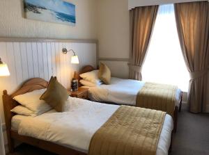 a hotel room with two beds and a window at Bacchus Hotel in Sutton on Sea