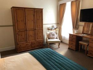 a bedroom with a bed and a cabinet and a chair at Bacchus Hotel in Sutton on Sea