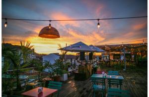 een patio met tafels en stoelen en een zonsondergang op de achtergrond bij Selina Casco Viejo Panama City in Panama-Stad