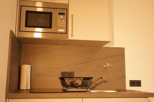 eine Mikrowelle über einer Küchentheke mit Spüle in der Unterkunft Vivo Apartments at Hospitals in Herne