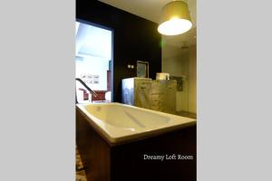 uma casa de banho com uma banheira branca e um espelho. em Dreamy Loft em Malang