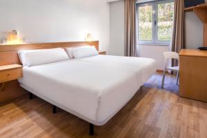 1 cama blanca grande en una habitación con escritorio en B&B HOTEL Braga Lamacaes en Braga