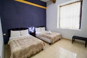 a bedroom with two beds and a window at Hotel Montejo in M&eacute;rida