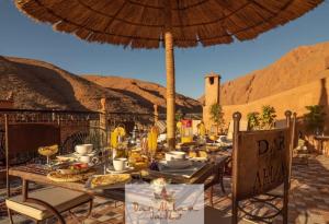 a table with food and an umbrella on a patio at Dar Ahlam Dades Hotel in Aït Ouaddar