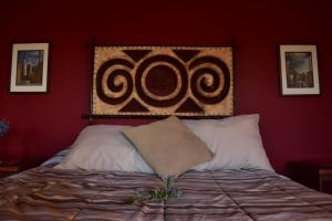 a bed in a red room with a large celticism at Bajo el Sol del Valle in Valle de Guadalupe