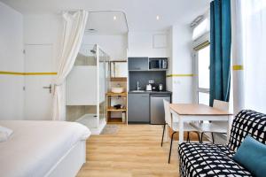 a bedroom with a bed and a table and a kitchen at cosy independant studio proche gare et jardin in Paris