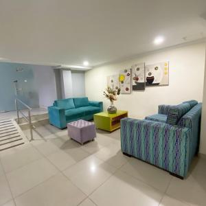 a living room with two blue couches and a table at Hotel Puerta de Oro in Barranquilla