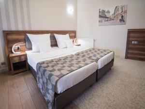 a hotel room with a large bed and a desk at Hotel Miodowa in Kraków