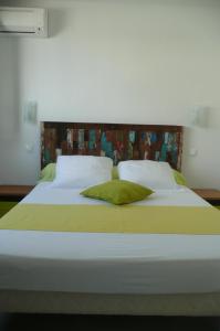 - un grand lit blanc avec des draps et des oreillers verts dans l'établissement Douceurs Caraïbes, Gîte Coco., à Bouillante