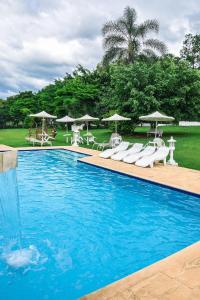 - une piscine avec des chaises longues et des parasols dans l'établissement Pousada Chalés da Felicidade, à Itu