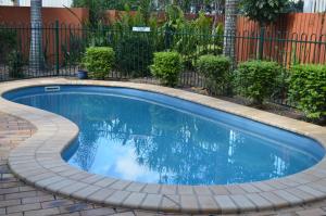 a small swimming pool with a brick patio and a fence at Airport Motel Brisbane in Brisbane