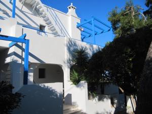 um edifício branco com acentos azuis na lateral em Villa Flora Studios & Apartments em Conca Specchiulla