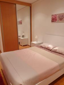 1 dormitorio con 1 cama blanca grande y espejo en Apartamento T3-S.PedroII, en Ponta Delgada