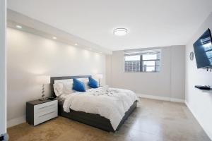 1 dormitorio blanco con 1 cama grande con almohadas azules en Ocean Reserve Luxury Condos Across from Sunny Isles Beach en Miami Beach
