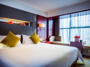 een hotelkamer met een groot wit bed met gele kussens bij Grand Mercure Xiamen Downtown-Free Welcome Fruit & Metro Station in Xiamen