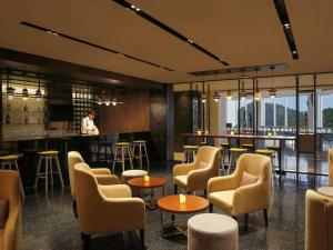 科钦Novotel Kochi Infopark的一间带椅子的餐厅和一间酒吧,酒吧的背景是一个人