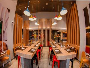 une grande salle à manger avec de longues tables et des chaises rouges dans l'établissement ibis Iquique, à Iquique