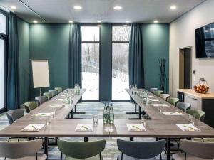 ibis Styles Stuttgart Vaihingen في شتوتغارت: قاعة اجتماعات كبيرة مع طاولة وكراسي طويلة