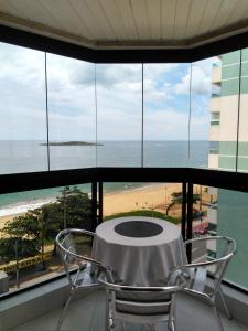 een tafel en stoelen in een kamer met uitzicht op het strand bij Residencial Atlanta in Vila Velha