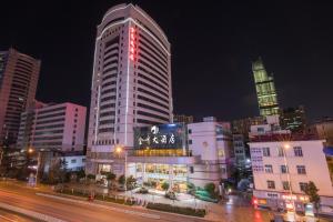 ein hohes Gebäude mit roten Lichtern in einer Stadt in der Unterkunft Kunming Golden Spring Hotel in Kunming