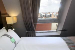a bedroom with a bed and a large window at Holiday Inn Paris Montmartre by IHG in Paris +105 photos