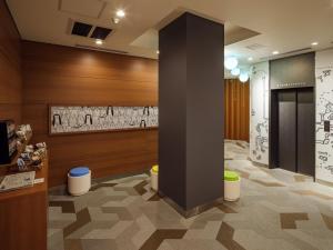 a lobby with a pillar and a wall with drawings on it at KOKO HOTEL Ikebukuro East in Tokyo