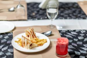 a sandwich and french fries on a plate with a glass of wine at Hotel Luciya in Cochin